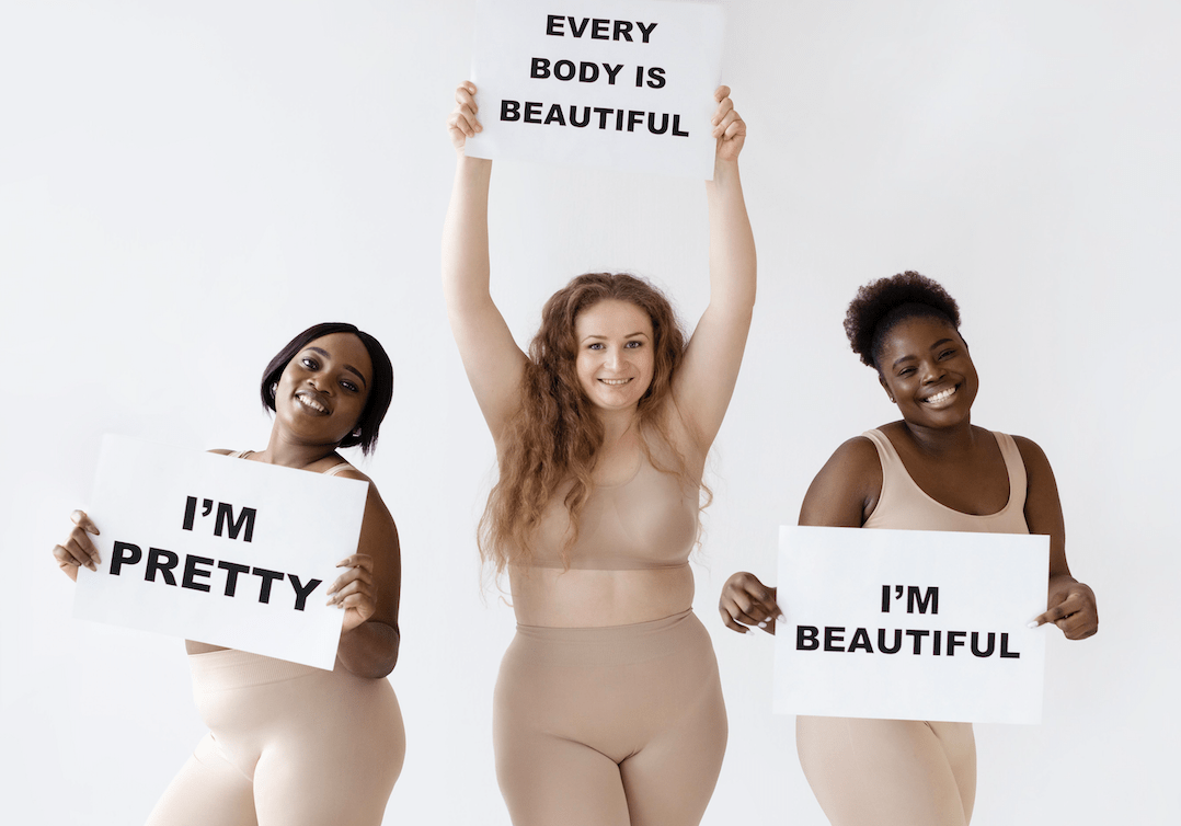 Mujeres celebrando el movimiento Body Positivity con pósteres en sus manos