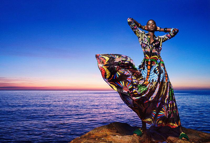 Mujer posando con los brazo levantados en una roca al lado del mar