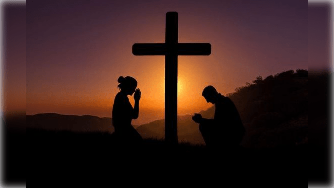 Jóvenes con fe rezando a la cruz