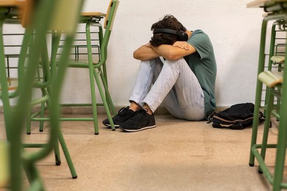 Adolescente sentado en el suelo del colegio por problemas de salud mental