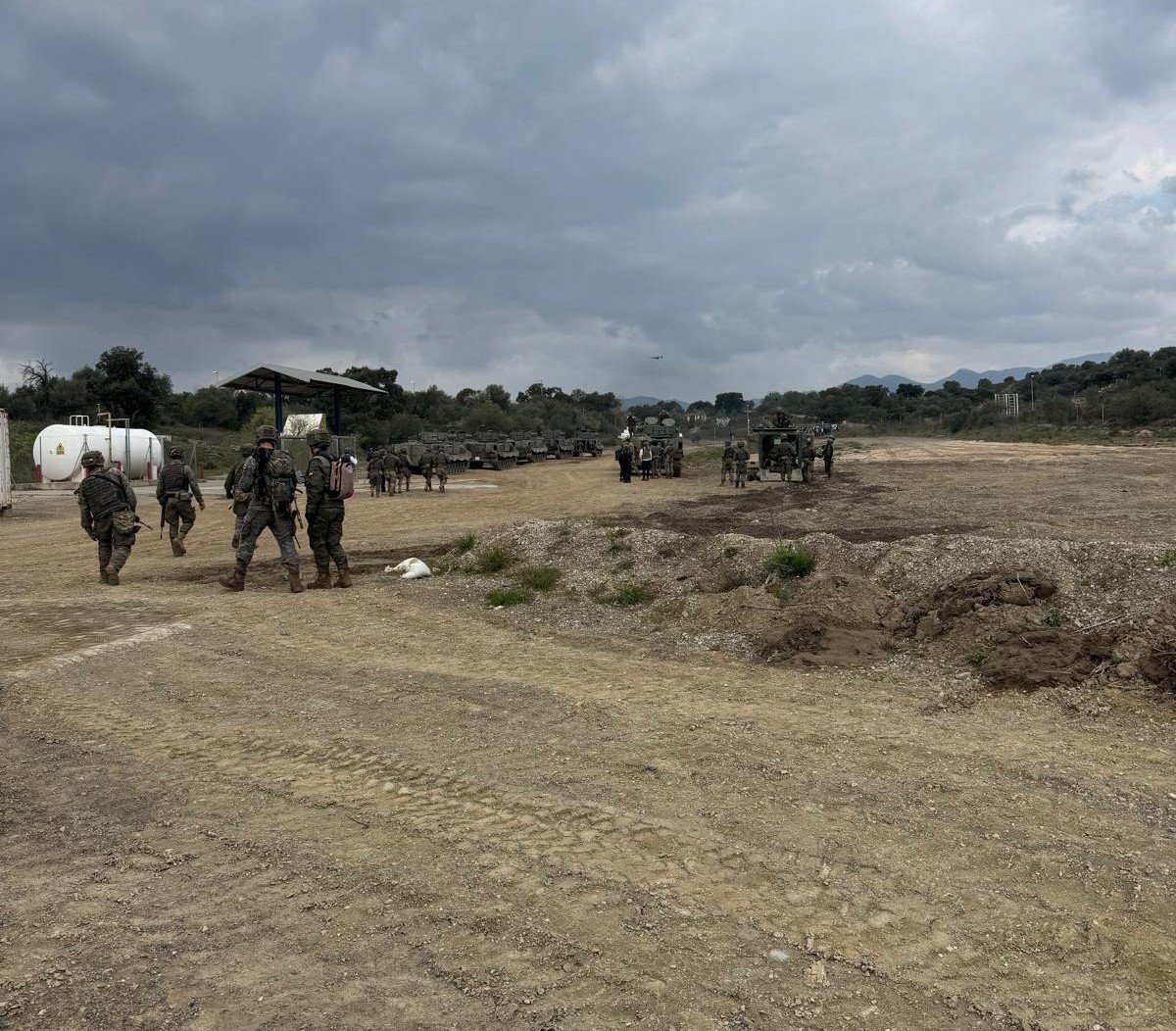 Soldados del ejército en un campo con carros de combate
